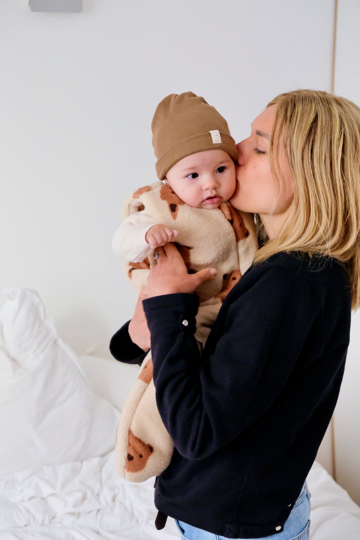maman embrassant son bebe avec gigoteuse hiver friends et bonnet marron