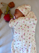 Bébé qui dort avec bonnet et emmailloteuse à fleurs