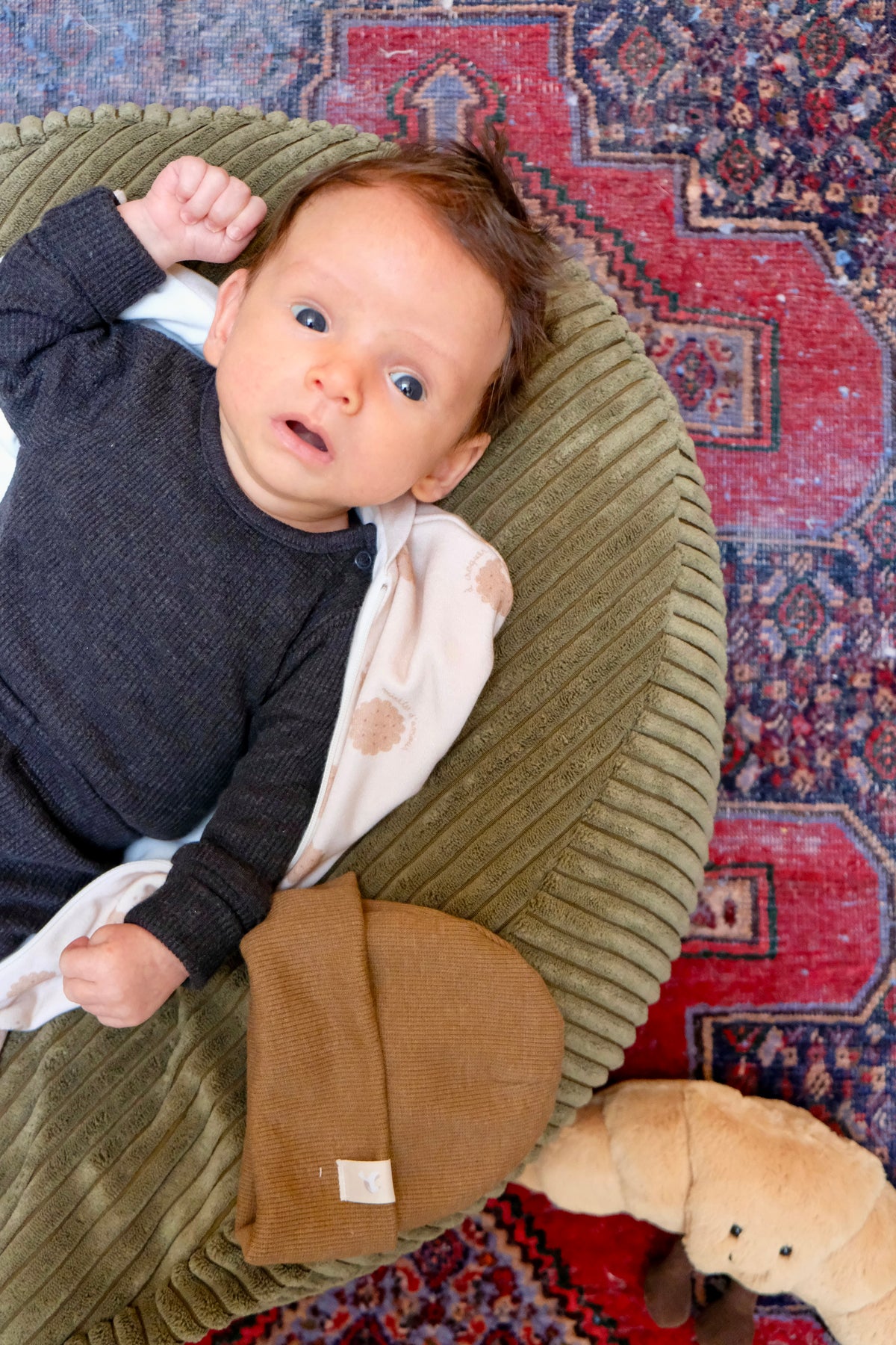 bebe éveillé sur nid bag matcha en tenue bébé noire avec bonnet à côté
