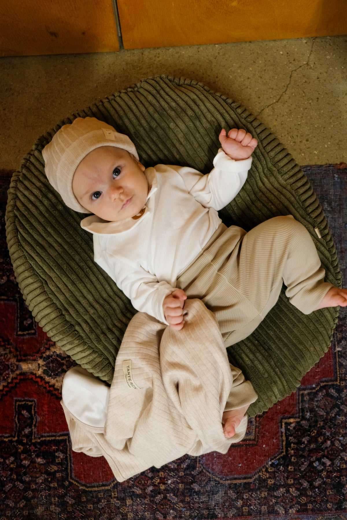 bébé posé sur nid matcha avec un bonnet de naissance nougat