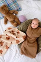 bebe ouvrant les yeux emmailloté sur nid et couverture