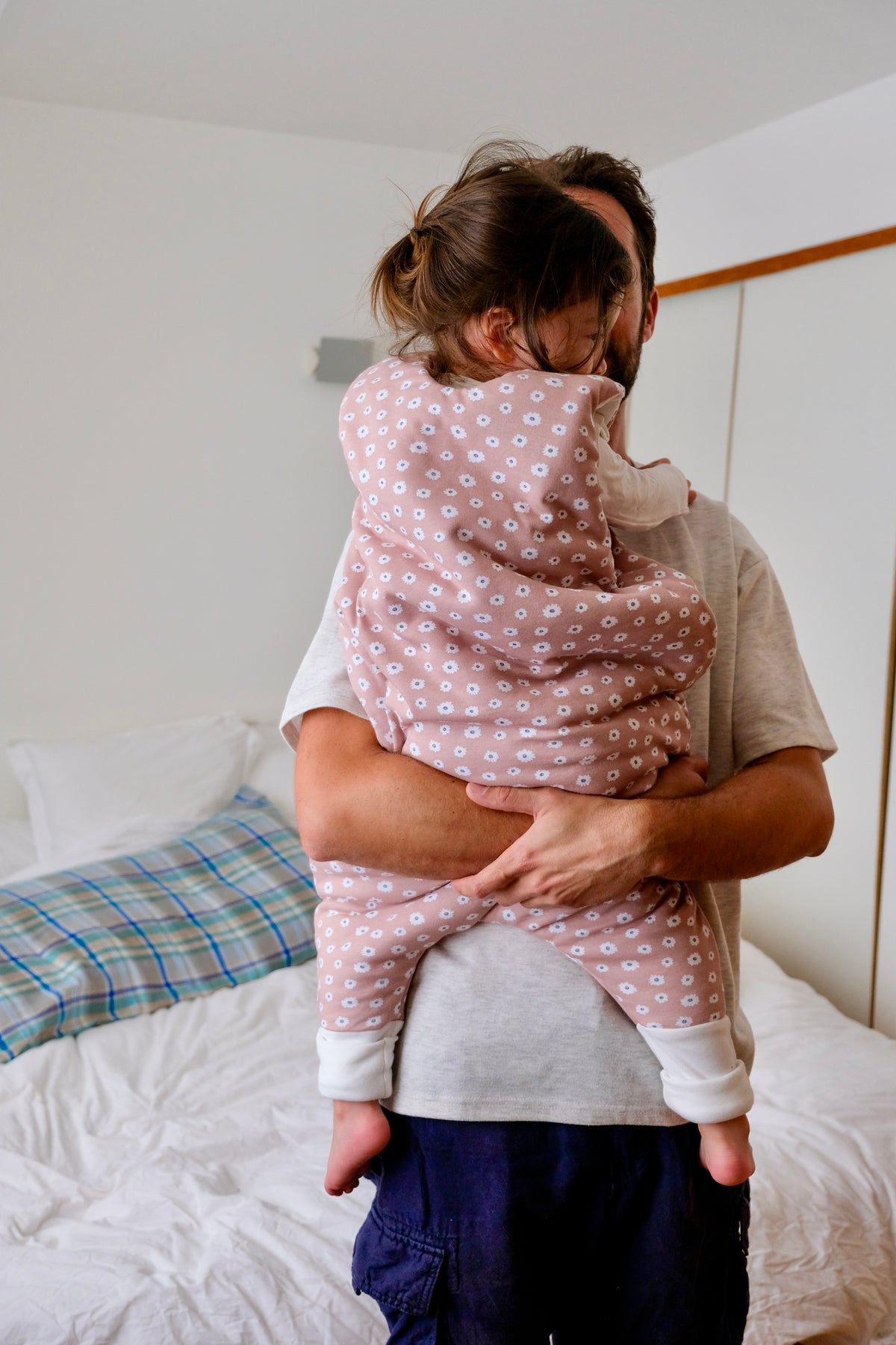 bébé dans les bras de son papa avec gigoteuse à pieds guimauve