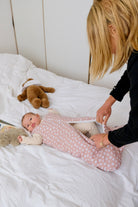 maman changeant son enfant en gigoteuse hiver guimauve rose fleurs