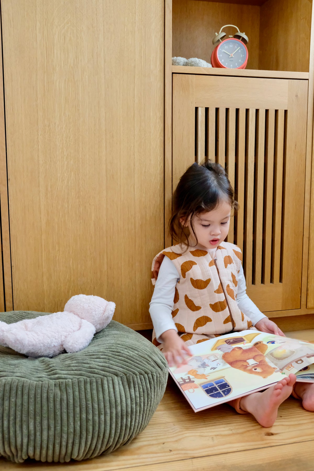 enfant fille lisant un livre dans sa chambre a cote d'un nid et d'une peluche